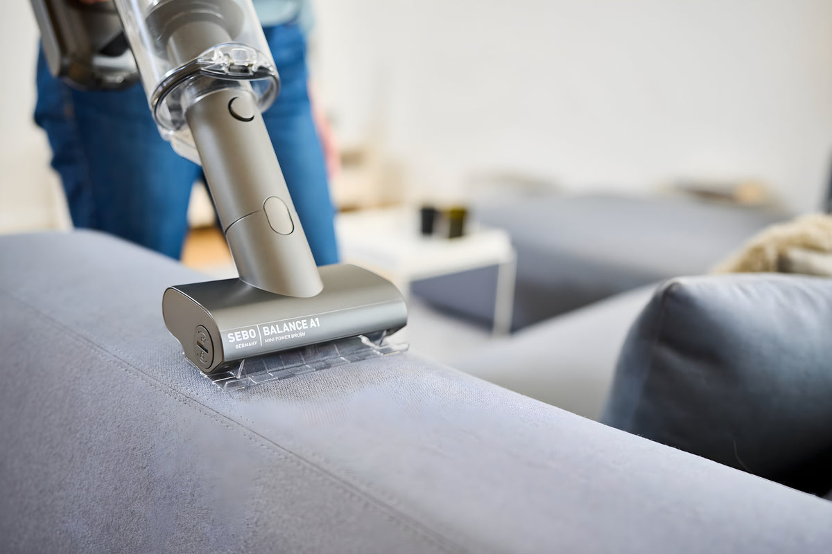SEBO Balance A1 mini power brush cleaning a sofa.