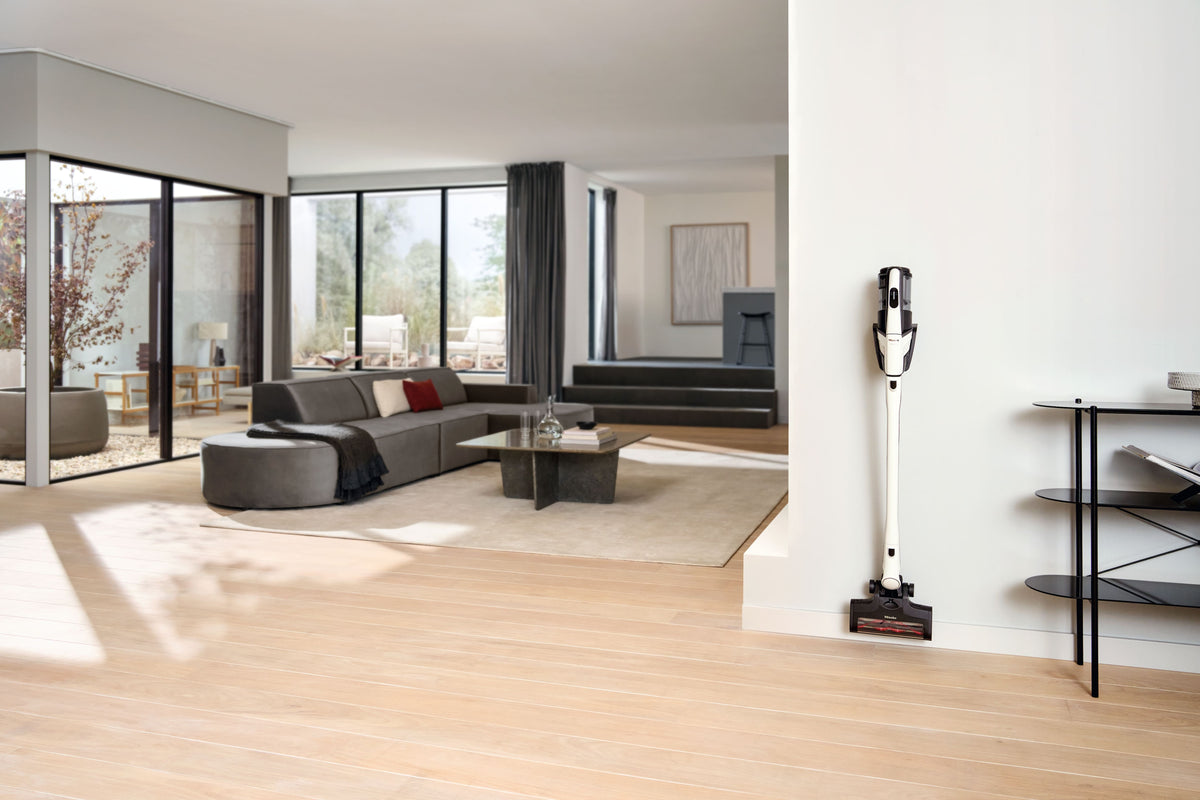 Miele Triflex HX3 in Brilliant White standing in its park position in a sunlit living room.