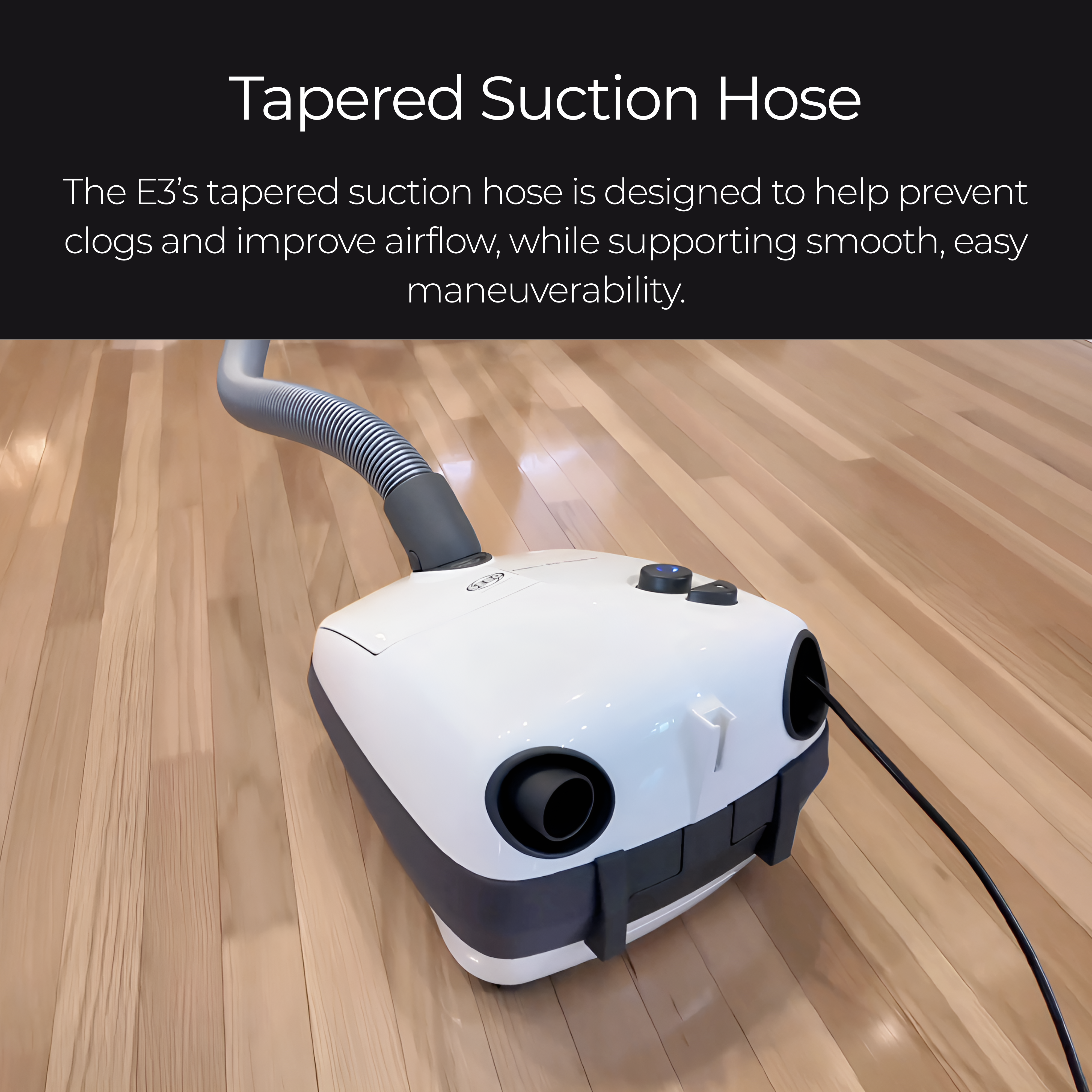 A white and dark gray Sebo E3 vacuum cleaner with a tapered suction hose, shown on a light wood floor.