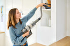 SEBO Balance A1 handheld with extension hose dusting a shelf.