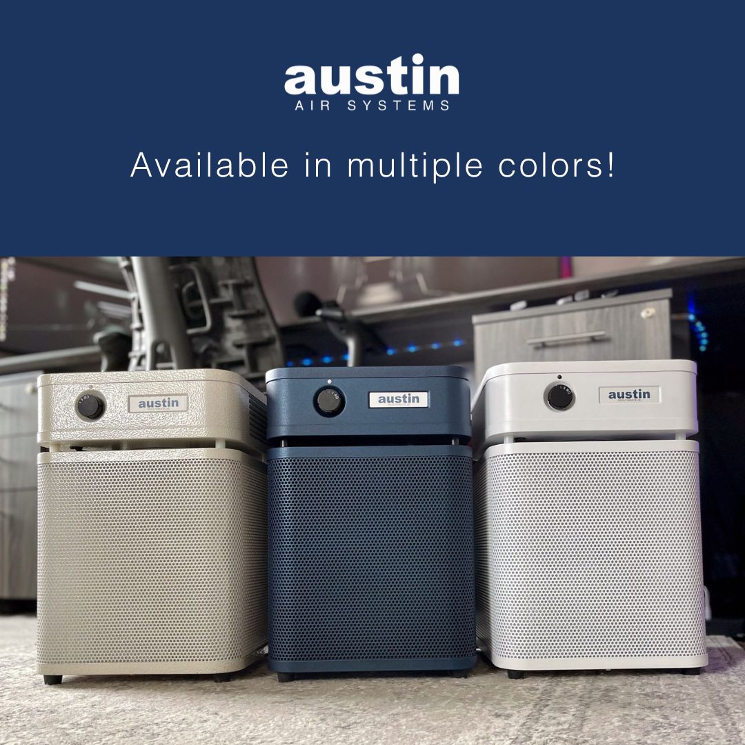 Three Austin Air HealthMate Junior purifiers in different colors on a carpeted floor