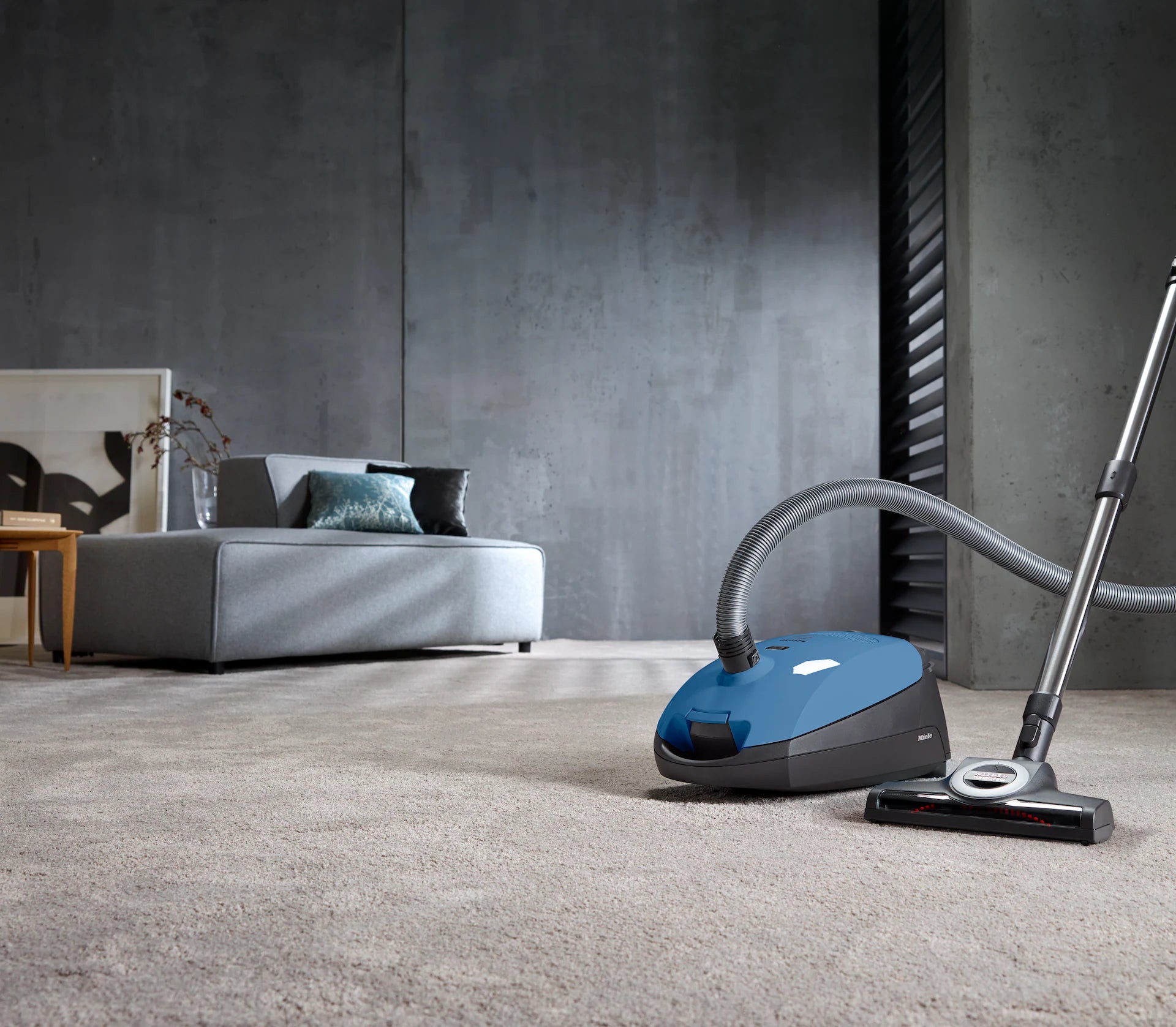 Miele Classic C1 Turbo Team in Tech Blue cleaning a carpeted room.