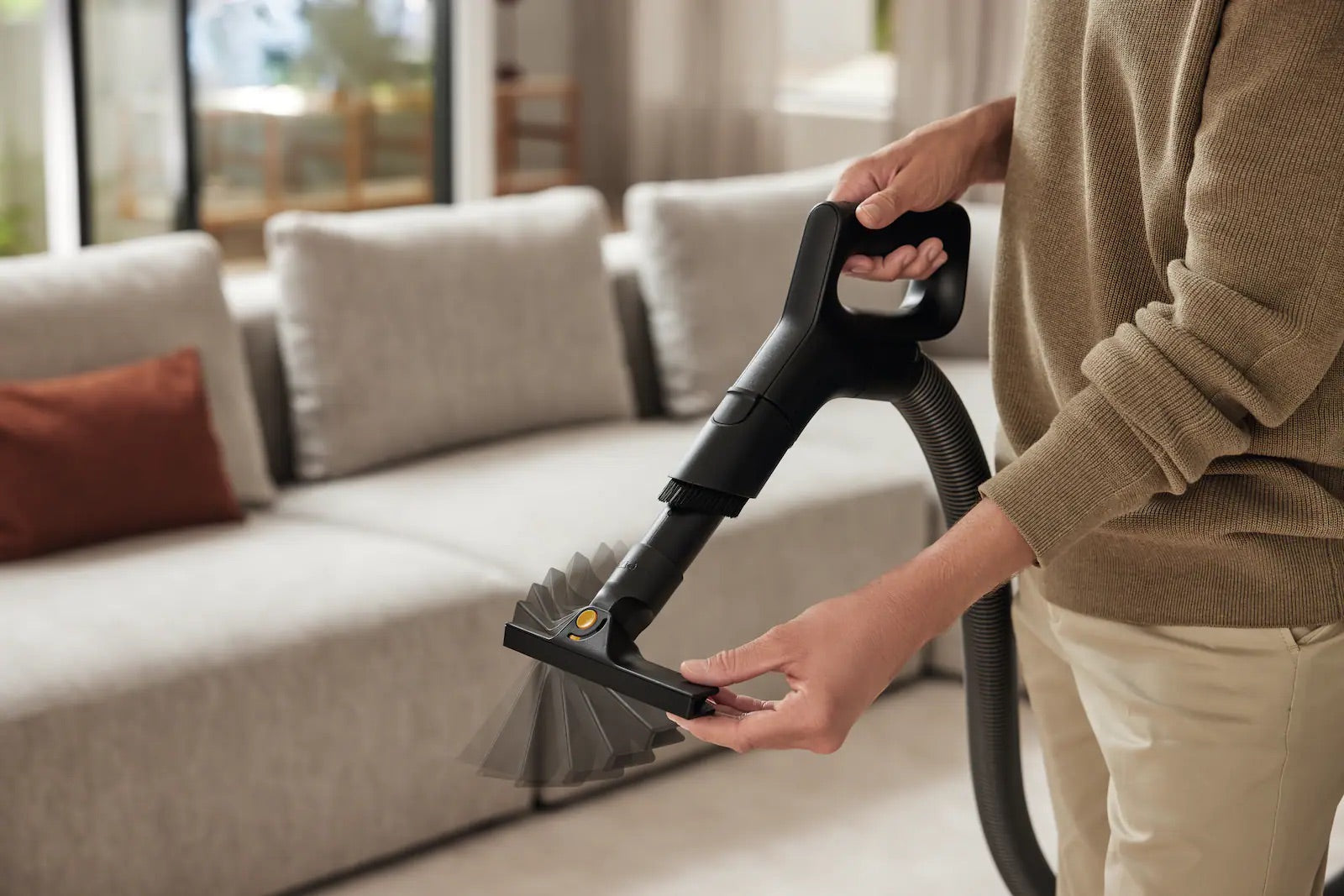 Miele Guard 2-in-1 crevice and upholstery tool cleaning a sofa.