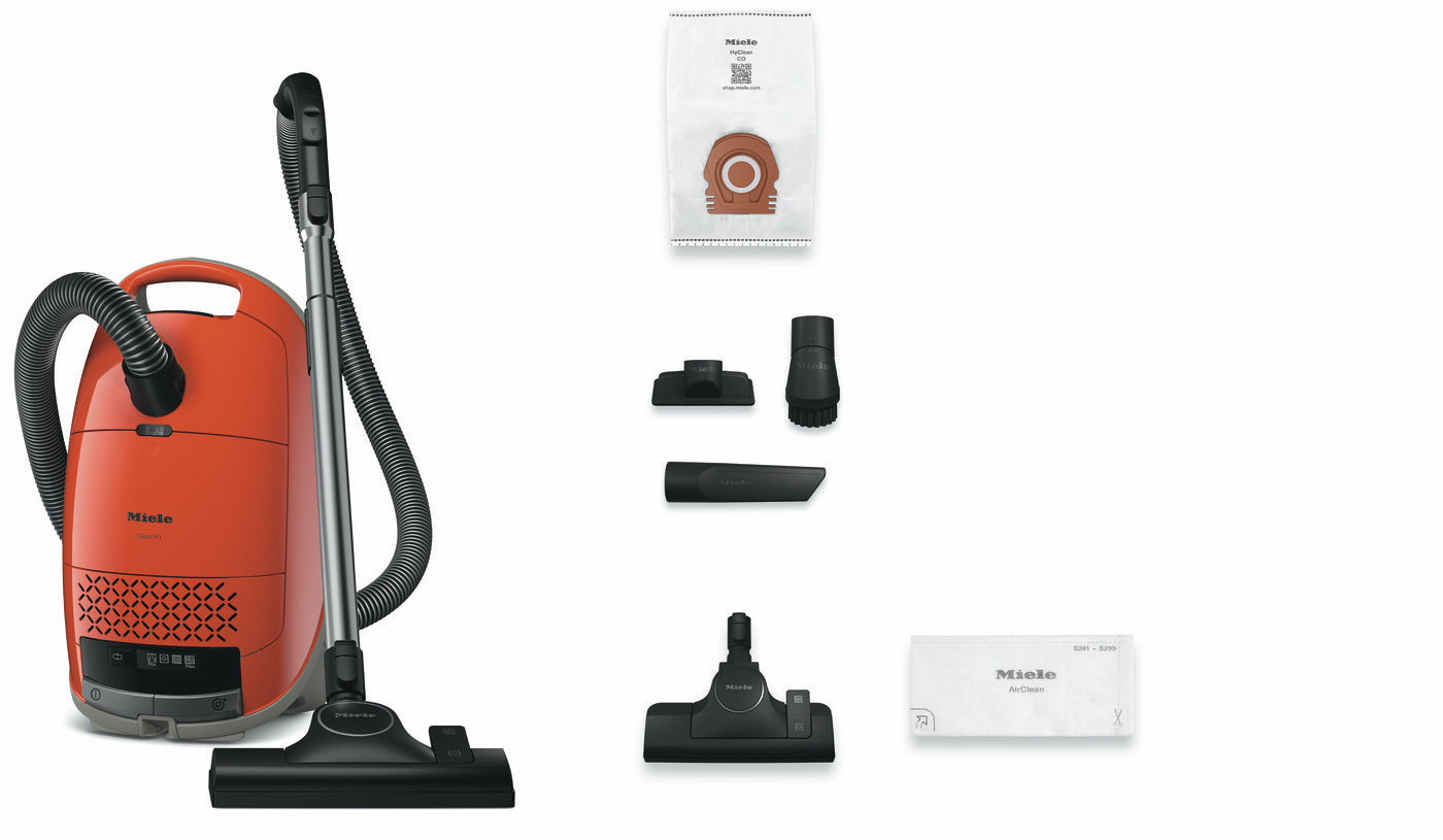 Miele Guard M1 Terra Red canister vacuum shown with its included accessories and instruction manual.