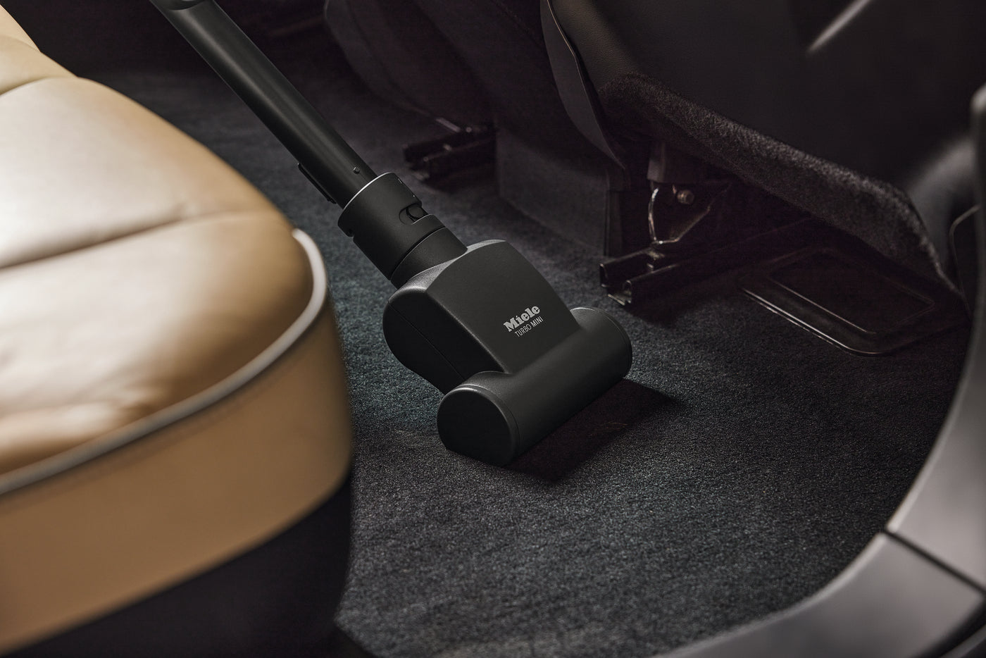 Miele STB 101 mini turbobrush cleaning a car floor mat.
