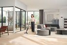 Woman vacuuming a hard floor in a bright living room with the Miele Triflex HX3 Hardfloor in Casa Grey.