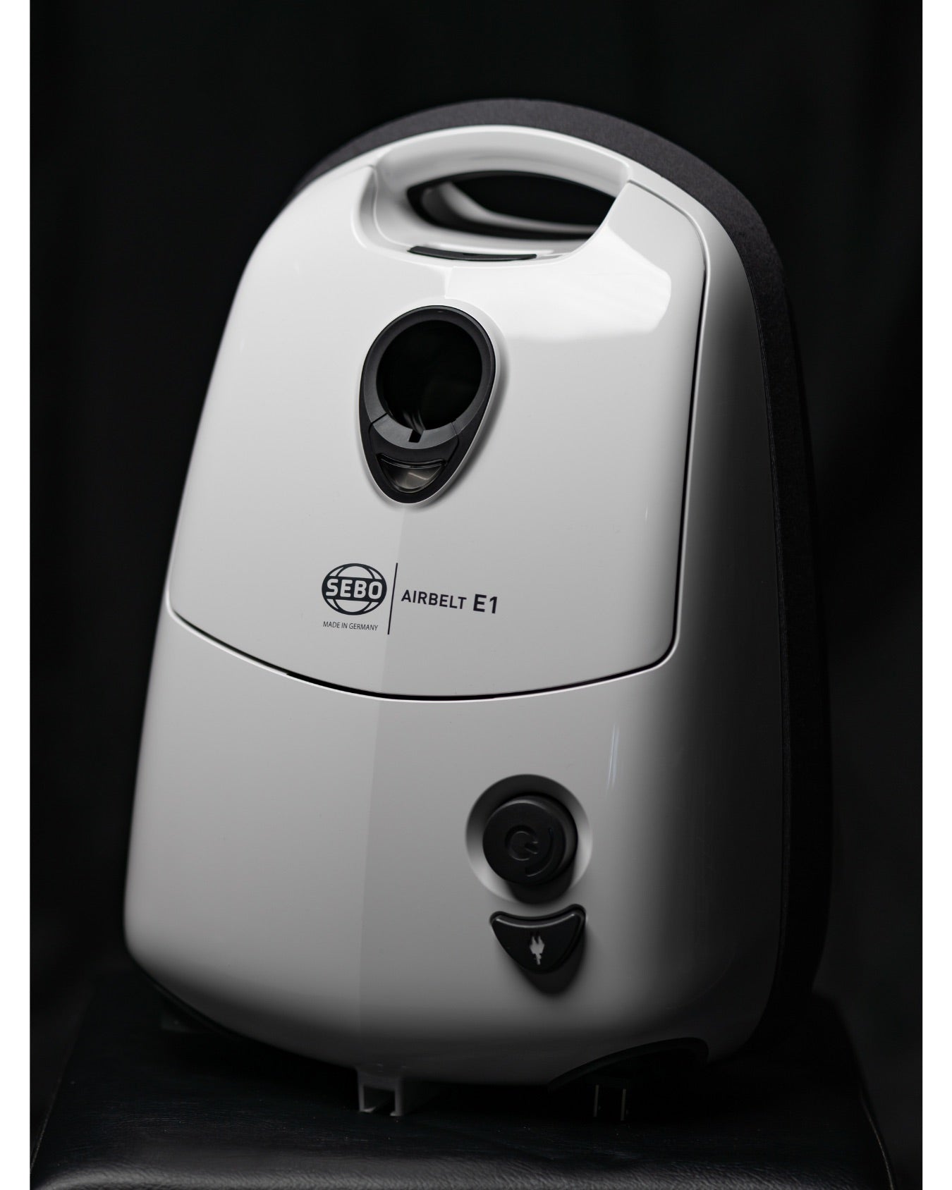Close-up of the white SEBO Airbelt E1 Kombi canister vacuum's front panel and logo.